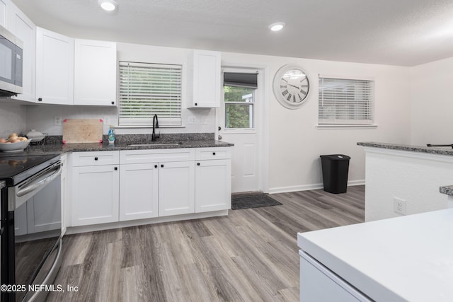 3165 Victoria Park Rd, Jacksonville, FL 32216 - kitchen with a sink, electric stove, white cabinetry, stainless steel microwave, and light wood-type flooring
