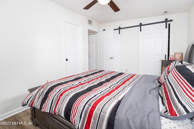 3165 Victoria Park Rd, Jacksonville, FL 32216 - bedroom with ceiling fan, visible vents, a barn door, wood finished floors, and baseboards