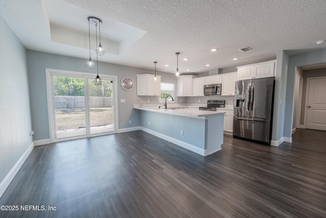 kitchen featuring appliances with stainless steel finishes, light countertops, a peninsula, recessed lighting, and visible vents