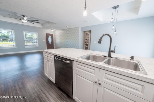 kitchen with stainless steel dishwasher, a sink, open floor plan, a tray ceiling, and dark wood-type flooring