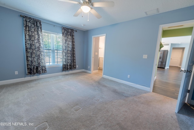 carpeted spare room with baseboards, ceiling fan, and visible vents