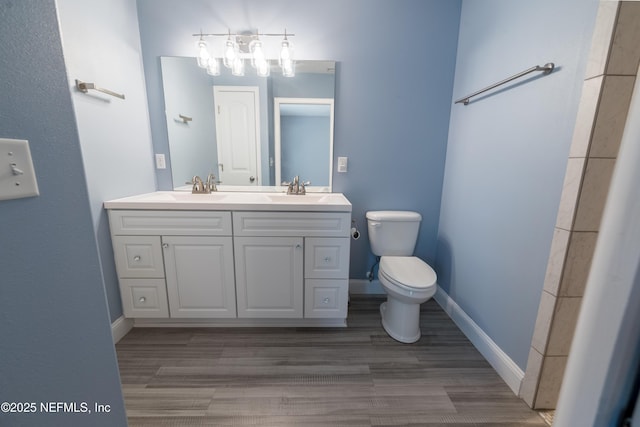 full bath featuring double vanity, a sink, wood finished floors, and toilet