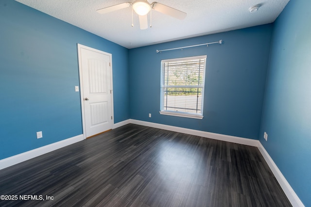 empty room featuring a ceiling fan, baseboards, dark wood-style floors, and a textured ceiling