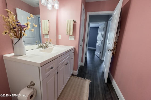 bathroom featuring baseboards, wood finished floors, and vanity