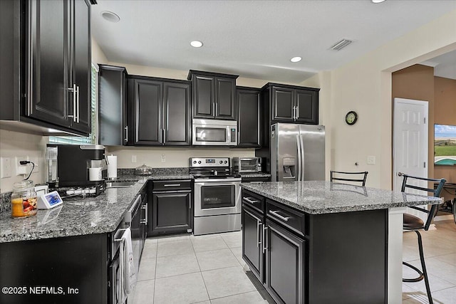 229 Adelanto Ave, Saint Augustine, FL 32092 - kitchen featuring stainless steel appliances, dark cabinetry, light tile patterned flooring, a kitchen island, and recessed lighting