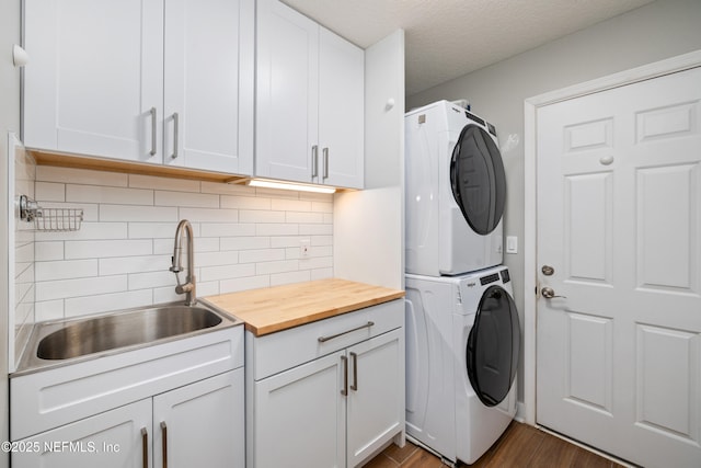 14526 Starbuck Springs Way, Jacksonville, FL 32258 - laundry area featuring stacked washer / dryer, cabinet space, dark wood finished floors, and a textured ceiling