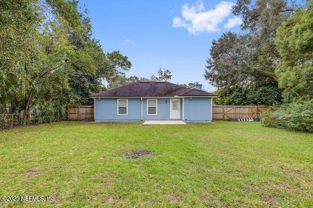 rear view of property with a lawn, a fenced backyard, and a patio area