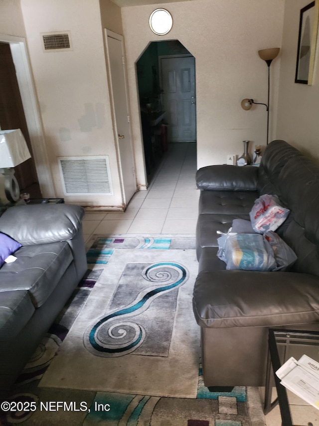 living area featuring visible vents, arched walkways, and light tile patterned flooring