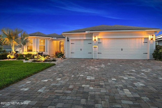 prairie-style home featuring a garage, decorative driveway, and a front yard