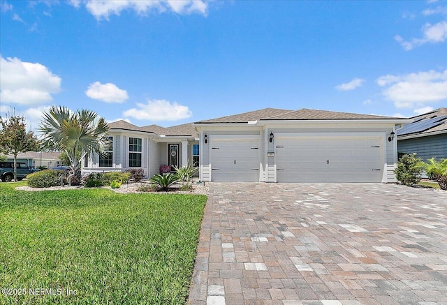 view of front of property featuring decorative driveway, a front yard, and a garage
