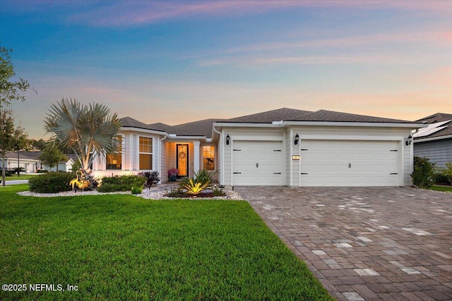 prairie-style house with an attached garage, decorative driveway, and a front yard