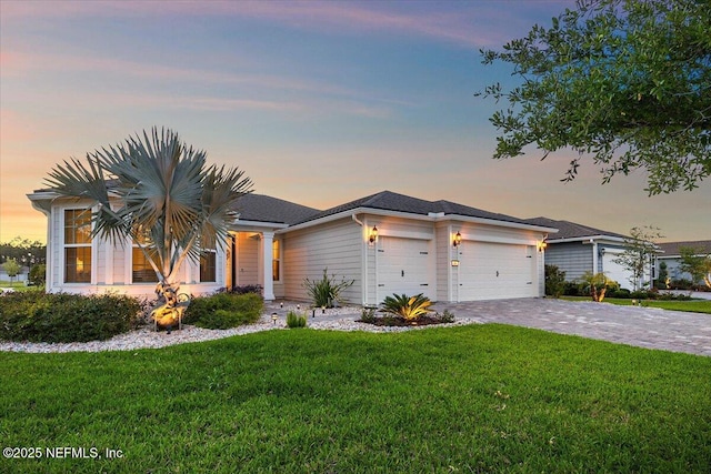 ranch-style house with a garage, decorative driveway, and a front lawn