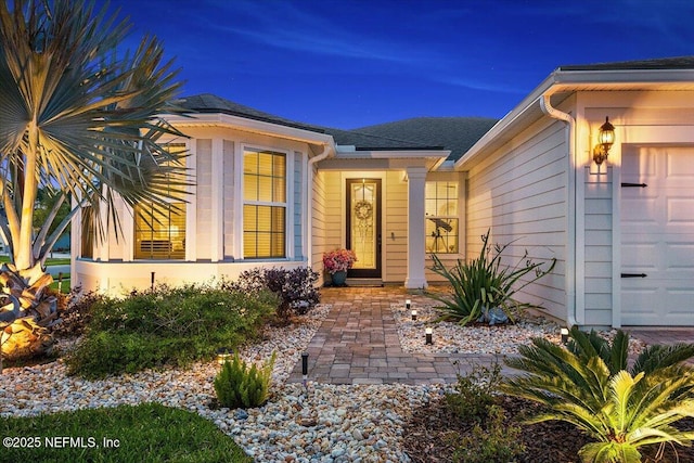 doorway to property featuring a shingled roof and an attached garage