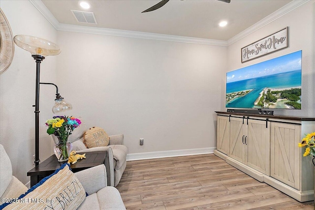 sitting room featuring visible vents, ornamental molding, light wood-style floors, and ceiling fan