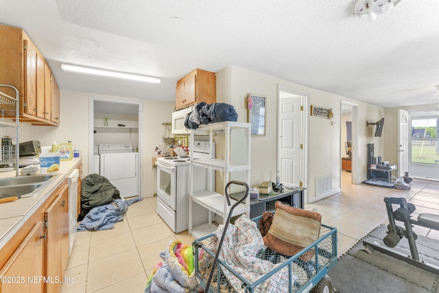 37885 Kings Ferry Rd, Hilliard, FL 32046 - kitchen featuring light tile patterned floors, white appliances, washing machine and dryer, and a textured ceiling