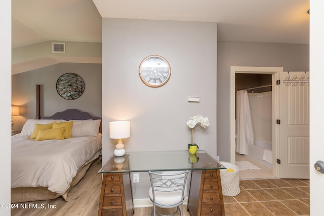 bedroom with tile patterned flooring, visible vents, and vaulted ceiling