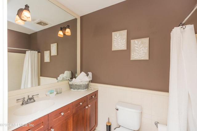 bathroom with toilet, a shower with curtain, a wainscoted wall, visible vents, and vanity