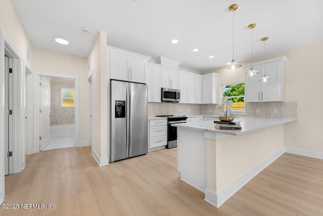 kitchen featuring light countertops, a peninsula, appliances with stainless steel finishes, and light wood-type flooring