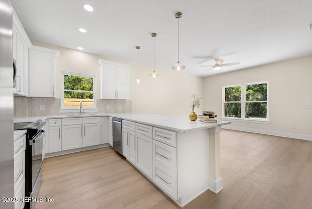 kitchen featuring a sink, dishwasher, light wood-style flooring, a peninsula, and black range with electric cooktop