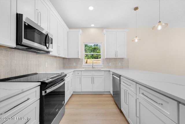 kitchen featuring backsplash, decorative light fixtures, appliances with stainless steel finishes, a sink, and white cabinets