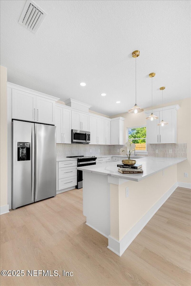 kitchen featuring visible vents, white cabinetry, tasteful backsplash, light wood finished floors, and appliances with stainless steel finishes