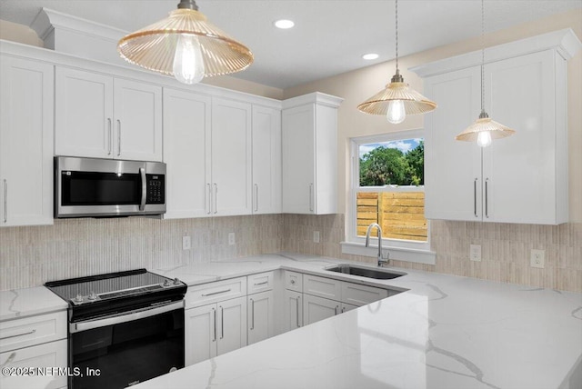 kitchen with electric range oven, light stone counters, a sink, stainless steel microwave, and white cabinetry