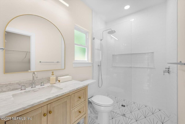 full bathroom featuring toilet, a tile shower, and vanity