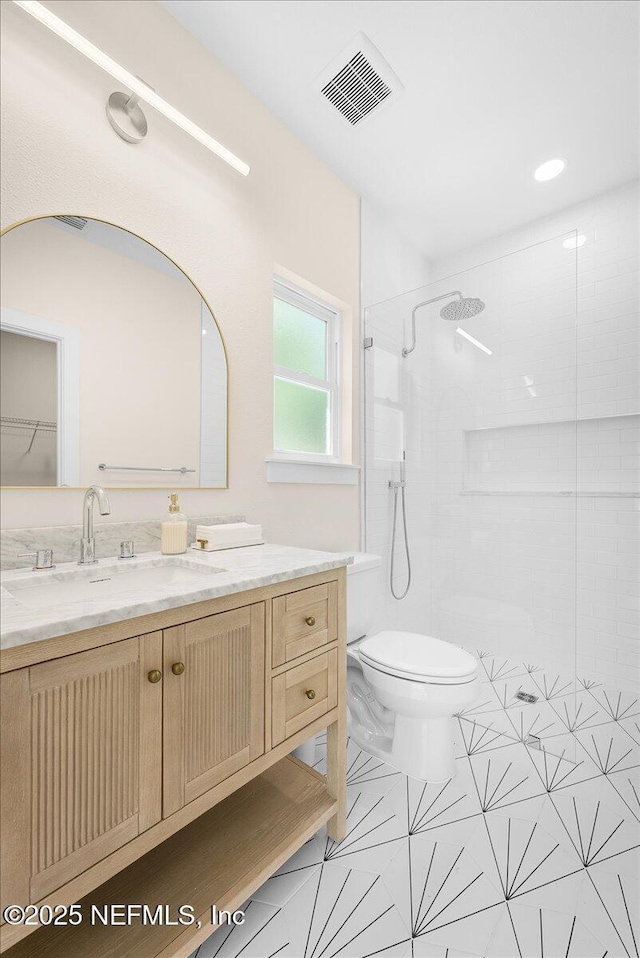 bathroom featuring visible vents, tile patterned flooring, a tile shower, vanity, and toilet