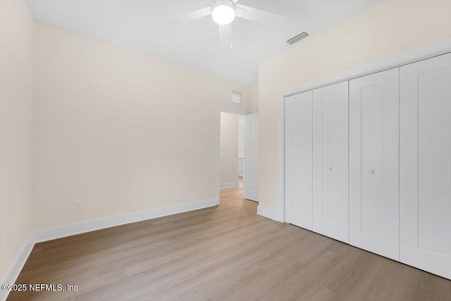 unfurnished bedroom featuring visible vents, baseboards, wood finished floors, and a closet