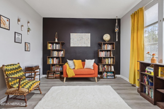 625 Oakleaf Plantation Pkwy Unit 1115, Orange Park, FL 32065 - sitting room with baseboards, an accent wall, and wood finished floors