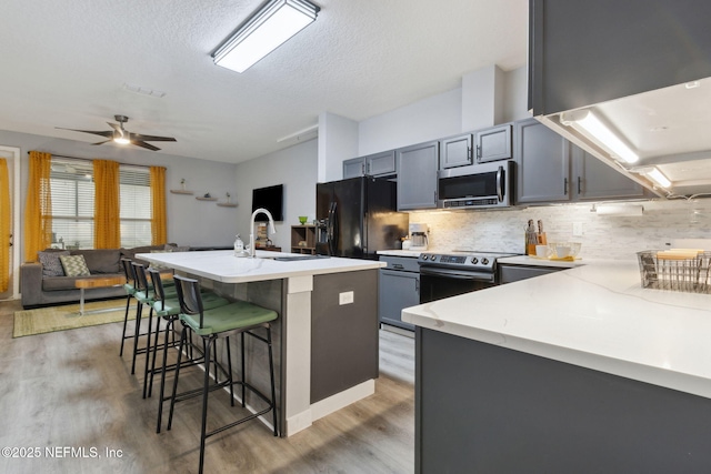 625 Oakleaf Plantation Pkwy Unit 1115, Orange Park, FL 32065 - kitchen featuring a breakfast bar area, a sink, decorative backsplash, light wood-style floors, and appliances with stainless steel finishes