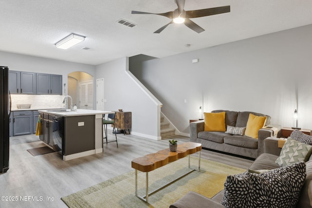 625 Oakleaf Plantation Pkwy Unit 1115, Orange Park, FL 32065 - living area with light wood finished floors, visible vents, ceiling fan, arched walkways, and stairs