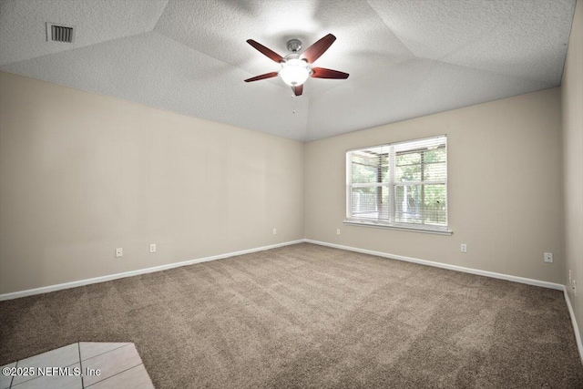 carpeted spare room with a textured ceiling, baseboards, visible vents, ceiling fan, and vaulted ceiling