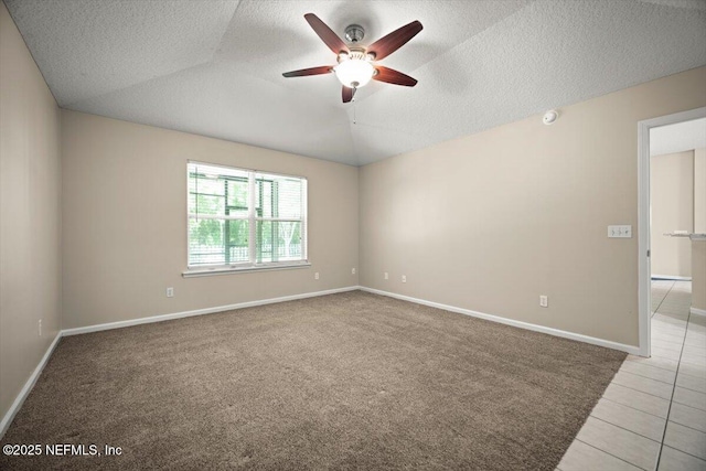 tiled empty room with a textured ceiling, baseboards, a ceiling fan, and carpet floors