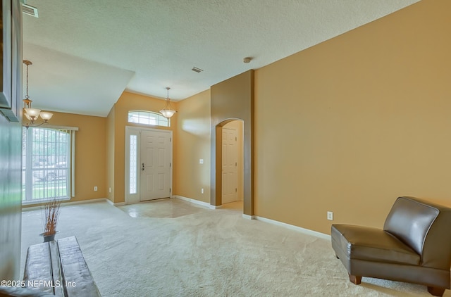 entrance foyer featuring lofted ceiling, visible vents, light carpet, arched walkways, and baseboards