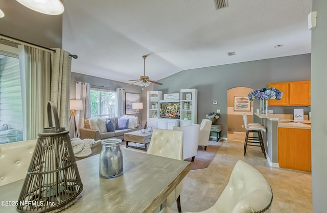 dining area featuring vaulted ceiling, visible vents, a ceiling fan, and arched walkways