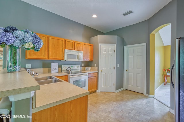 kitchen with light countertops, arched walkways, a sink, and white appliances