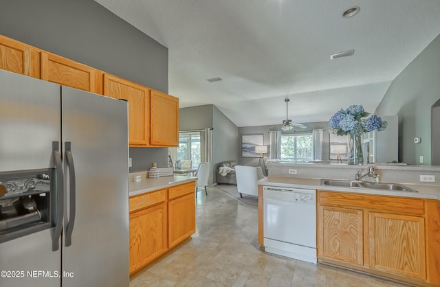 kitchen with a sink, light countertops, stainless steel fridge, a ceiling fan, and white dishwasher