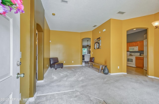 interior space featuring light carpet, arched walkways, and visible vents