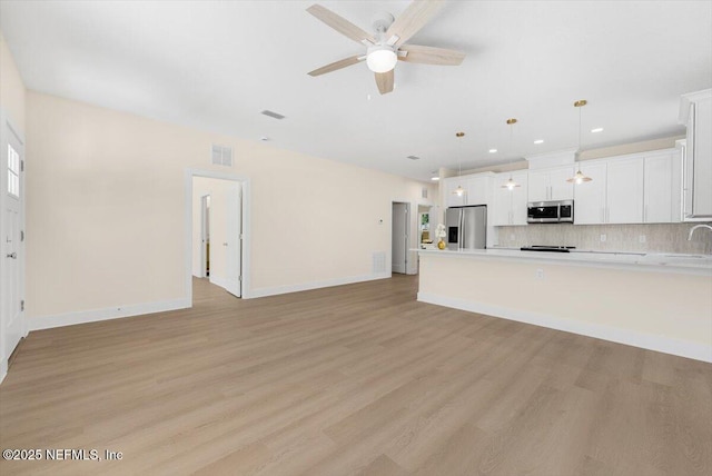 unfurnished living room with visible vents, a ceiling fan, light wood-style flooring, and baseboards
