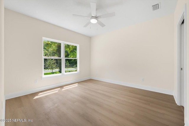 empty room featuring baseboards, ceiling fan, visible vents, and wood finished floors