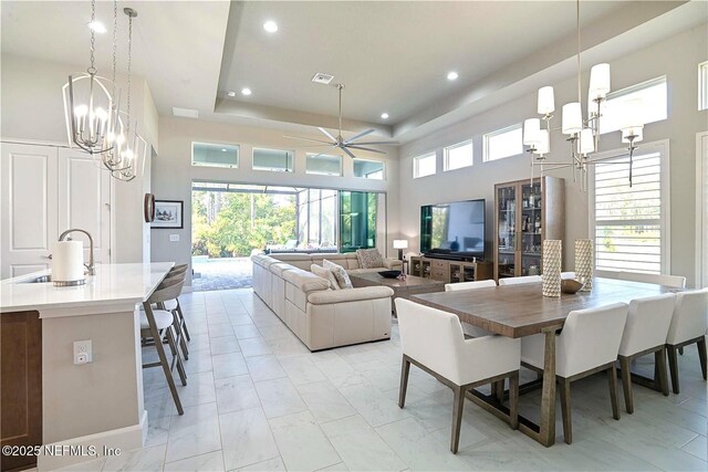 dining room featuring a chandelier, a raised ceiling, ceiling fan, recessed lighting, and light marble finish flooring