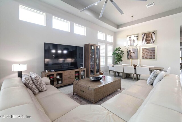 living area featuring ceiling fan, a chandelier, and a towering ceiling