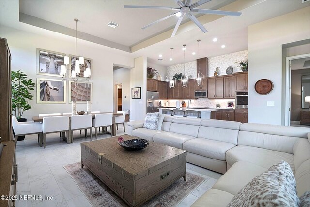 living room featuring a ceiling fan, a high ceiling, recessed lighting, and light marble finish floors