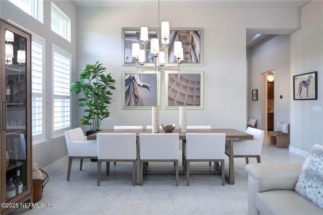 dining area featuring a chandelier, marble finish flooring, and baseboards