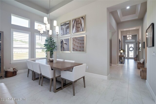 dining room featuring a chandelier, a high ceiling, plenty of natural light, and baseboards