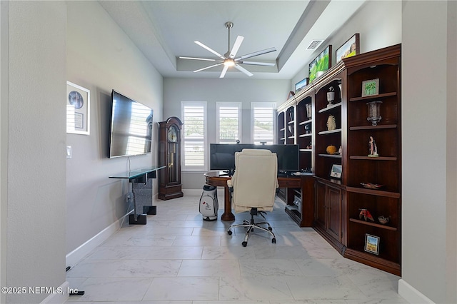 office space featuring a ceiling fan, baseboards, a raised ceiling, and light marble finish floors
