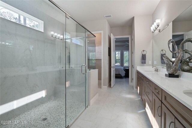 ensuite bathroom with a shower stall, marble finish floors, double vanity, and baseboards