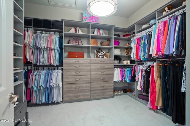 spacious closet featuring marble look tiles