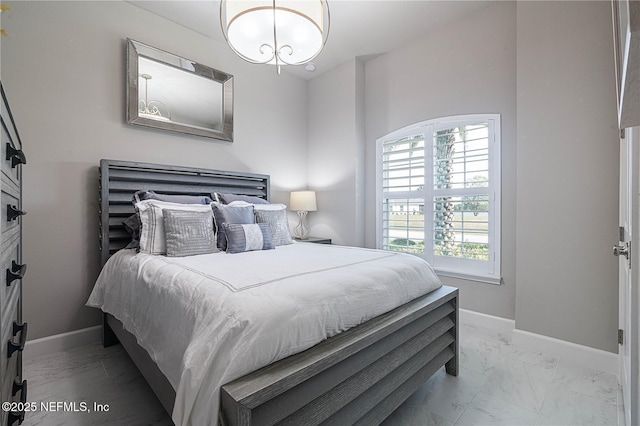 bedroom with marble look tile flooring, baseboards, and a chandelier